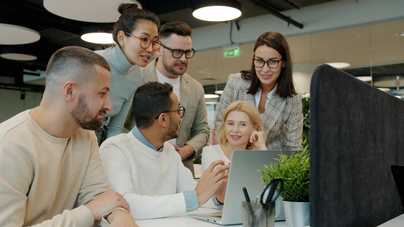 Team members collaborating around a laptop
